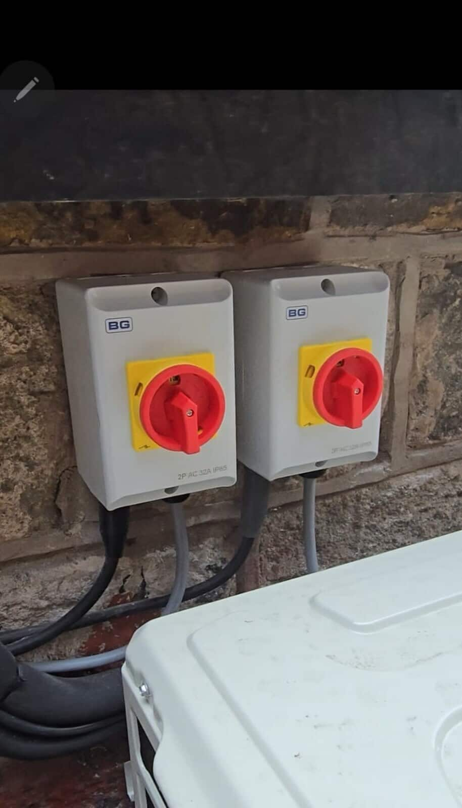 Two BG IP65 rotary isolator switches mounted on an exterior stone wall